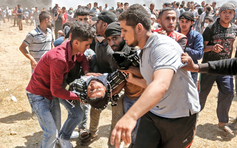 فلسطينيون يسعفون جريحاً في  اشتباكات مع قوات الاحتلال  بالقرب من حدود  غزة. أ.ف.ب