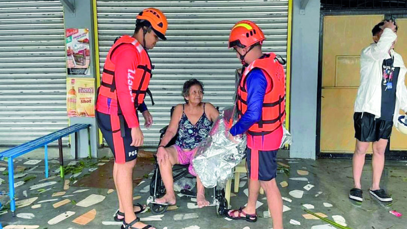 عمال الانقاذ يساعدون عجوز لم تتمكن من المشي بفعل الرياح والفيضانات. ي ب ا