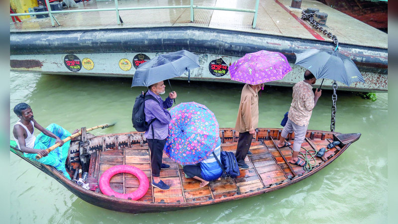 أشخاص يحملون مظلات أثناء عبورهم نهر بوريجانجا. إي.بي.إيه