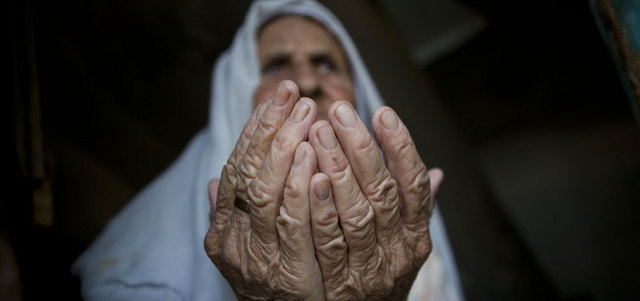 عجوز فلسطينية ترفع يديها بالدعاء في غزة.  أ.ف.ب