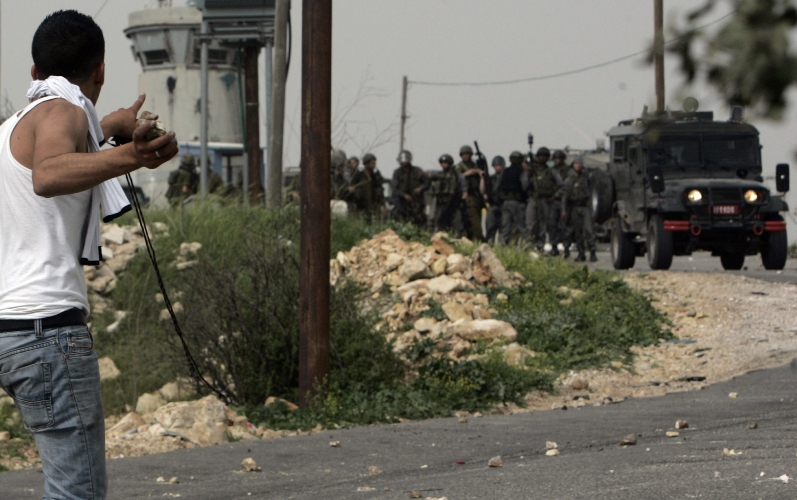 فتى فلسطيني يواجه بصحبة الحجر مجموعة إسرائيلية بكامل عتادها العسكري-أ.ف.ب