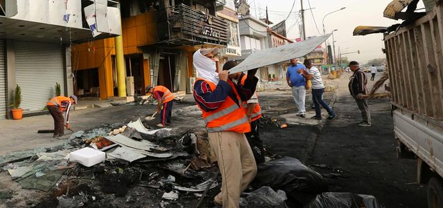 عمال البلدية ينظفون موقع انفجار سيارة مفخخة بحي المنصور في بغداد. أ.ب