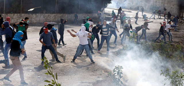 فلسطينيون يلقون الحجارة باتجاه قوات الاحتلال خلال اشتباكات بجانب الجدار العنصري قرب أبوديس. أ.ف.ب