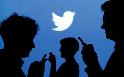 People holding mobile phones are silhouetted against a backdrop projected with the Twitter logo in this illustration picture taken in  Warsaw September 27, 2013. Twitter Inc, the eight-year-old online messaging service, gave potential investors their first glance at its financials on Thursday when it publicly filed its IPO documents, setting the stage for one of the most-anticipated debuts in over a year. Picture taken September 27.  REUTERS/Kacper Pempel (POLAND - Tags: BUSINESS TELECOMS LOGO)